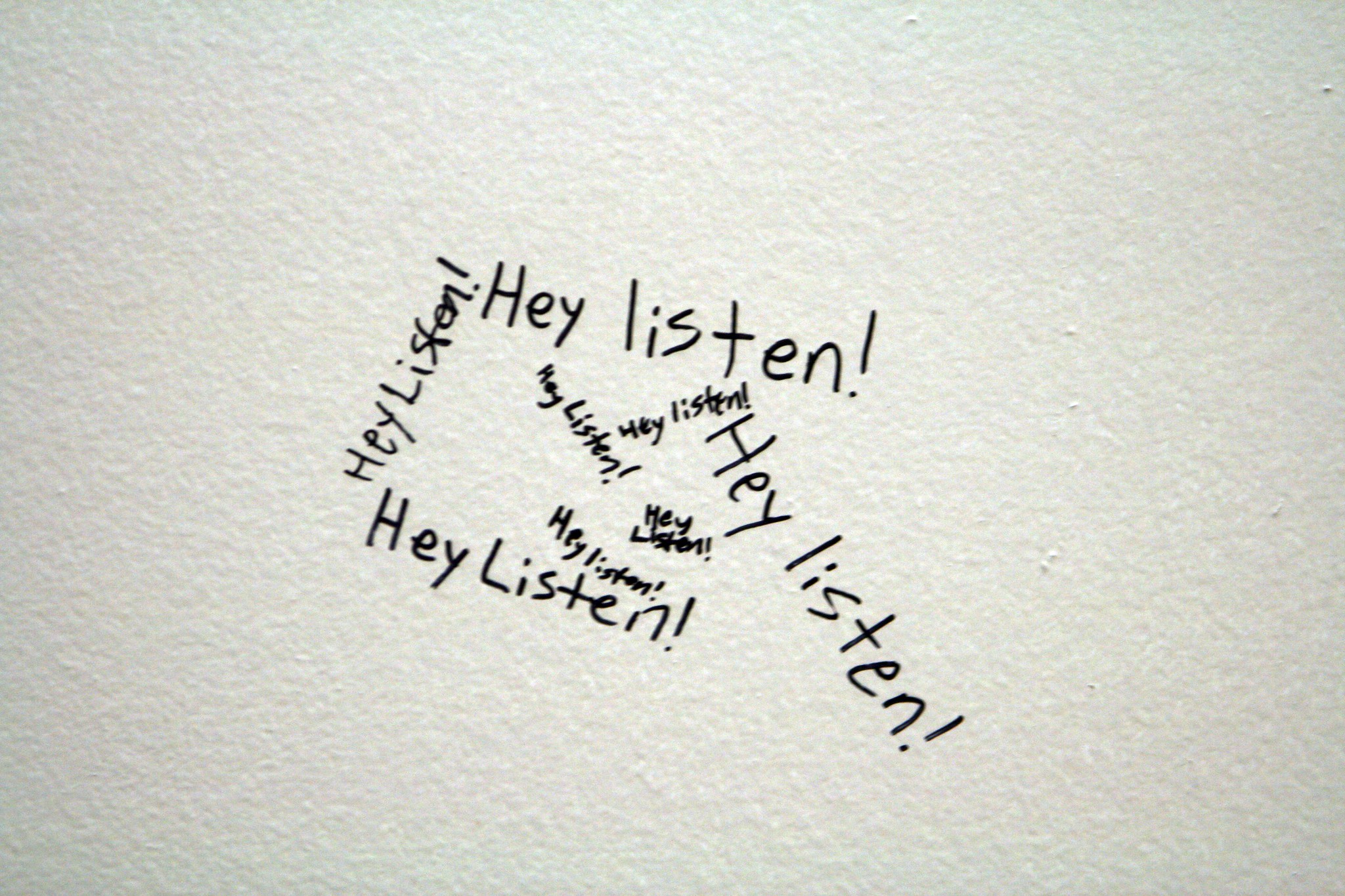 "Hey listen!" written multiple times on a wall.