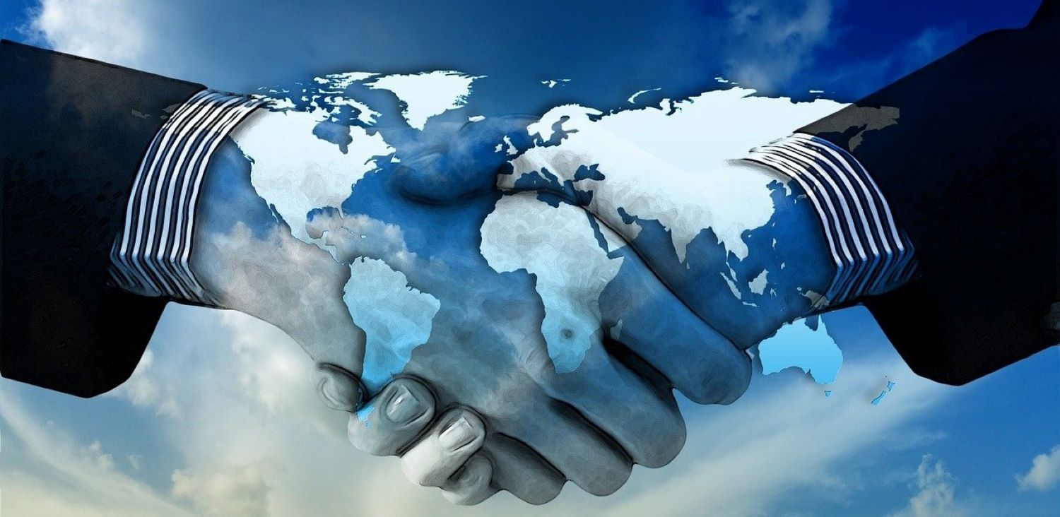 Shaking hands with an overlay of a map of the world.